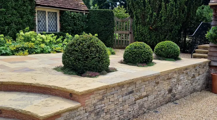 A landscaped patio with stone walling and topiary